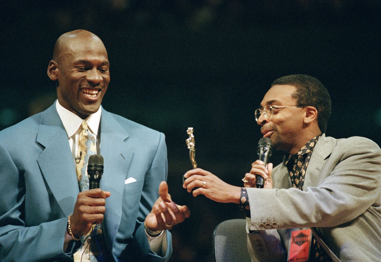 Basketball star Michael Jordan receives a statuette from Lee as Jordan's number was retired by the Chicago Bulls in 1994. Jordan was also receiving a 12-foot statue of himself outside of the United Center. Early in Jordan's career, Lee appeared with Jordan in many shoe commercials, playing his Mars Blackmon character.