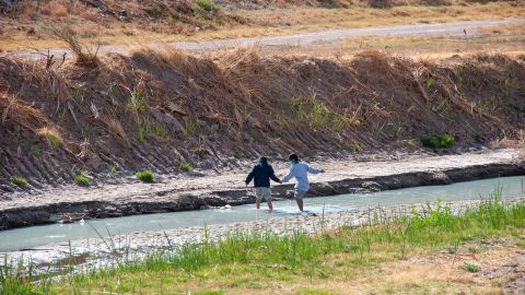 Two children cross the Rio Grande in Juarez, Mexico, on March 27, 2021, to surrender to a border patrol agent with the intention of requesting political asylum in the United States.