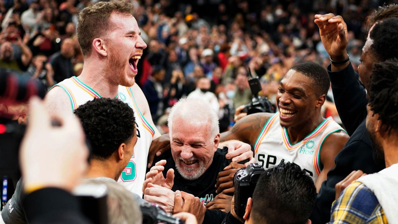 Gregg Popovich is surrounded by San Antonio Spurs players after he broke all-time wins record as NBA head coach.