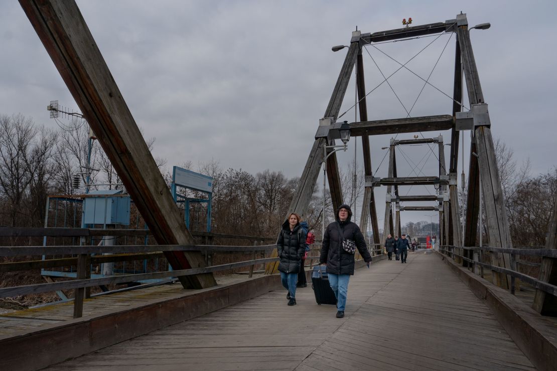 Ukrainian refugees cross the bridge spanning the Tisza river, connecting Ukraine with Romania.