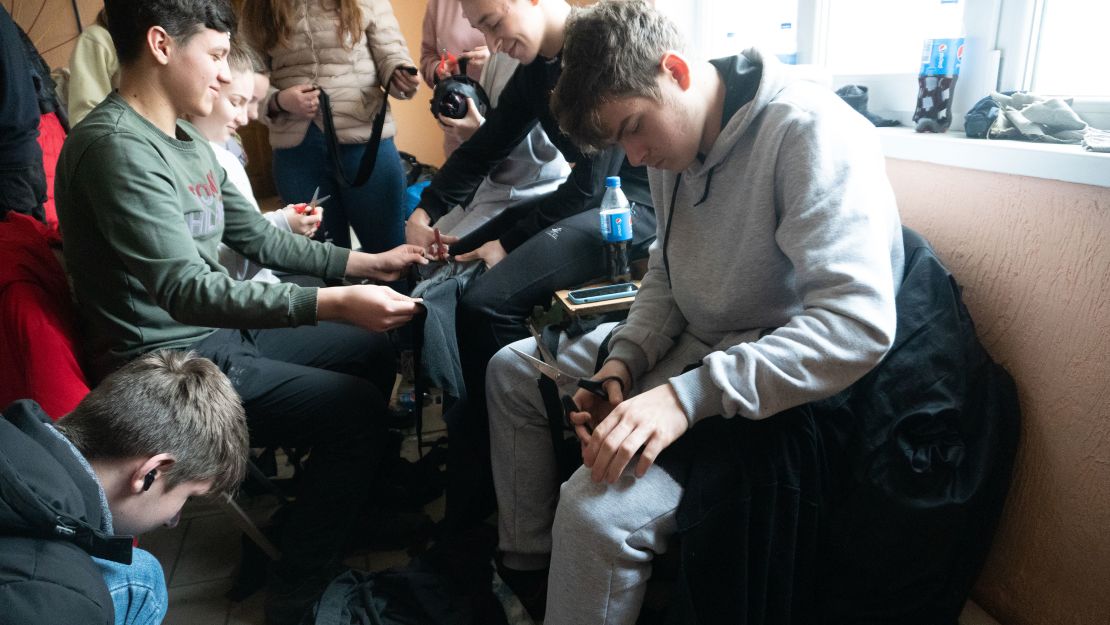 Children cutting up old T-shirts, pants and jackets to tie military camouflage nets.