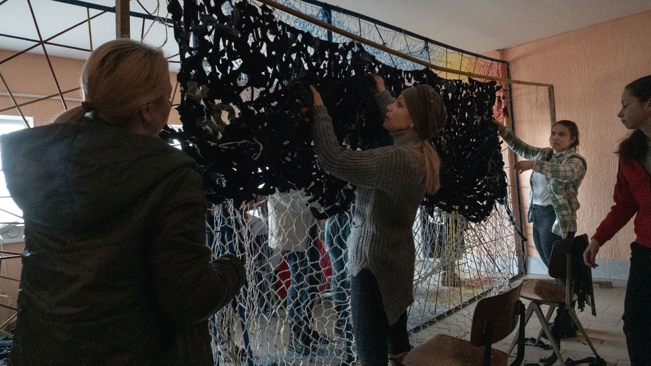 Women and teens in Solotvyno, Ukraine, knotting military camouflage nets that will be sent to the front lines.