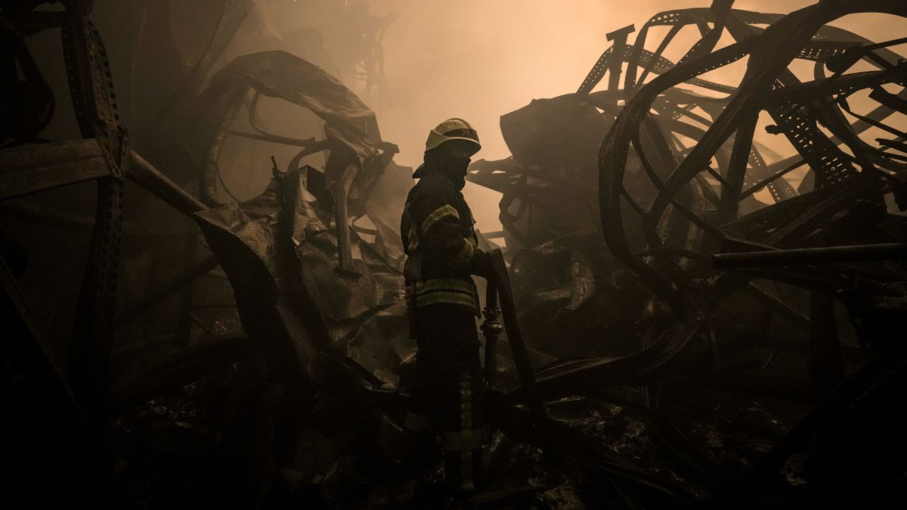 A Ukrainian firefighter drags a hose inside a large food products storage facility which was destroyed by an airstrike in the early morning hours on the outskirts of Kyiv, Ukraine, Sunday, March 13, 2022.
