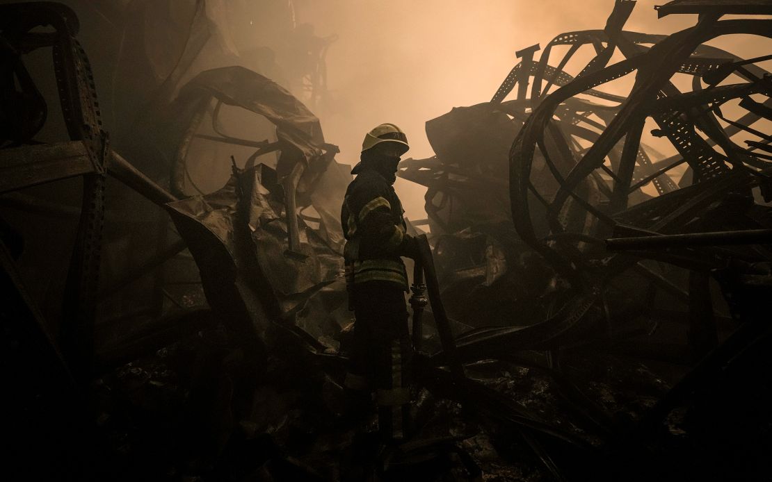 A Ukrainian firefighter drags a hose inside a large food products storage facility which was destroyed by an airstrike in the early morning hours on the outskirts of Kyiv, Ukraine, Sunday, March 13, 2022.