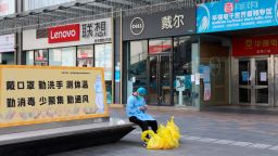 A janitor checks his phone outside closed shops in Huaqiangbei area, the world's biggest electronics market, in Shenzhen in south China's Guangdong province on March 14, 2022. The city, an economic powerhouse bordering Hong Kong, went into the Covid-19 lockdown on Sunday.  