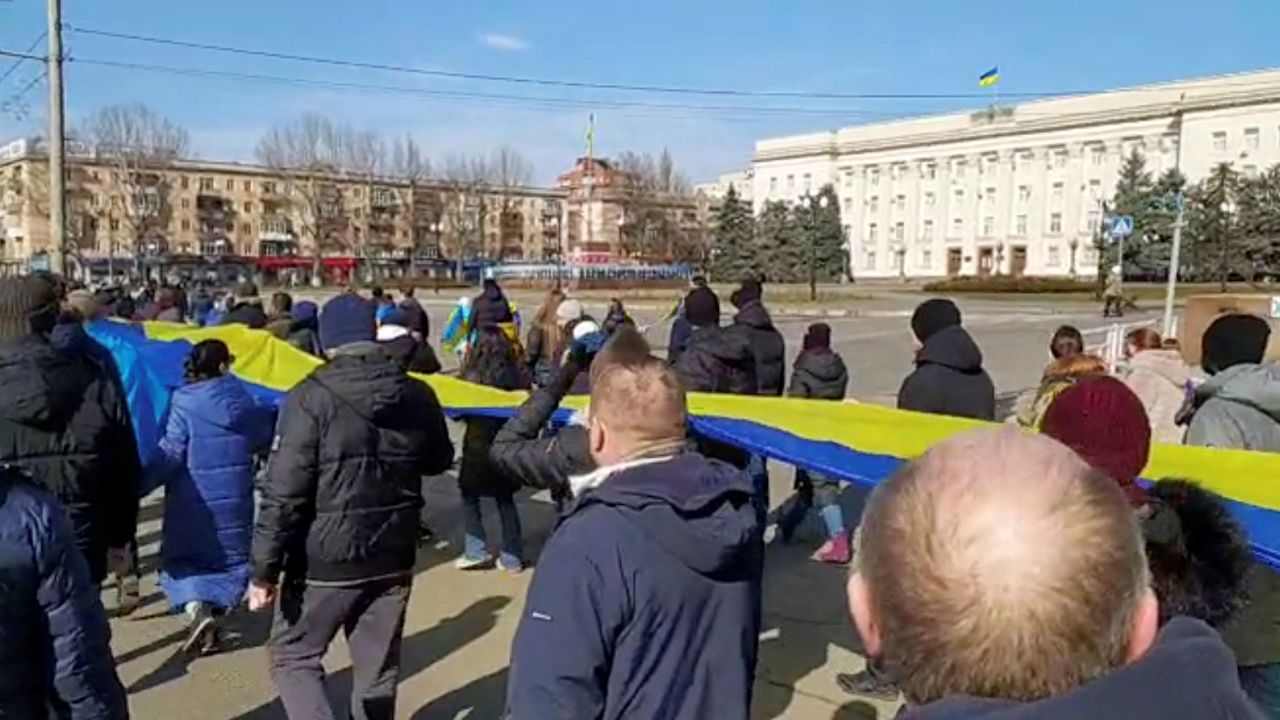 Live-streamed footage shows people carrying a banner in the colors of the Ukrainian flag as they protest amid Russia's invasion of Ukraine, in Kherson, on March 13.
