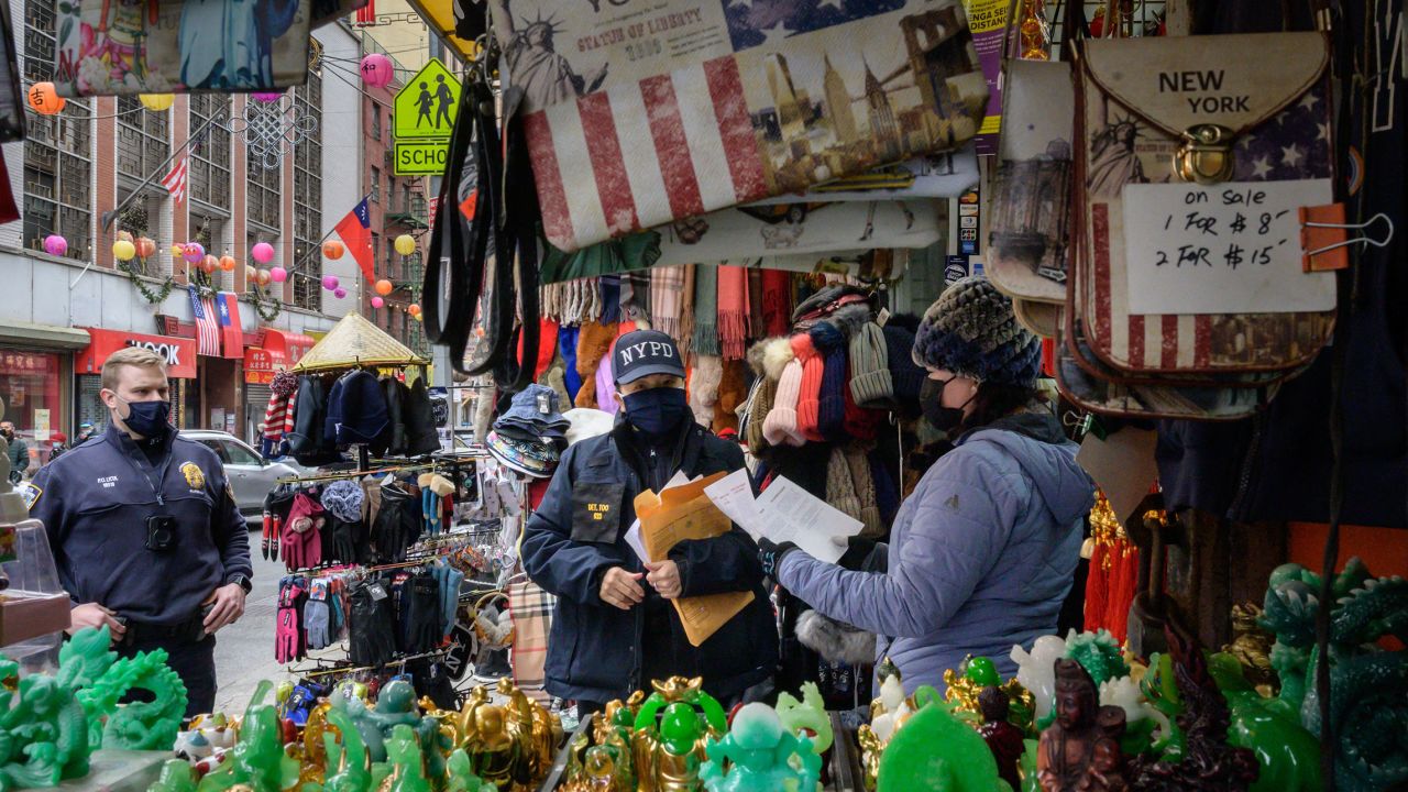 A police officer in New York's Chinatown hands out leaflets with information on how to report on hate crimes on March 17, 2021.