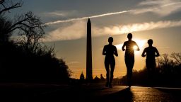 People run along the National Mall at sunrise in Washington, DC, on March 15, 2022.