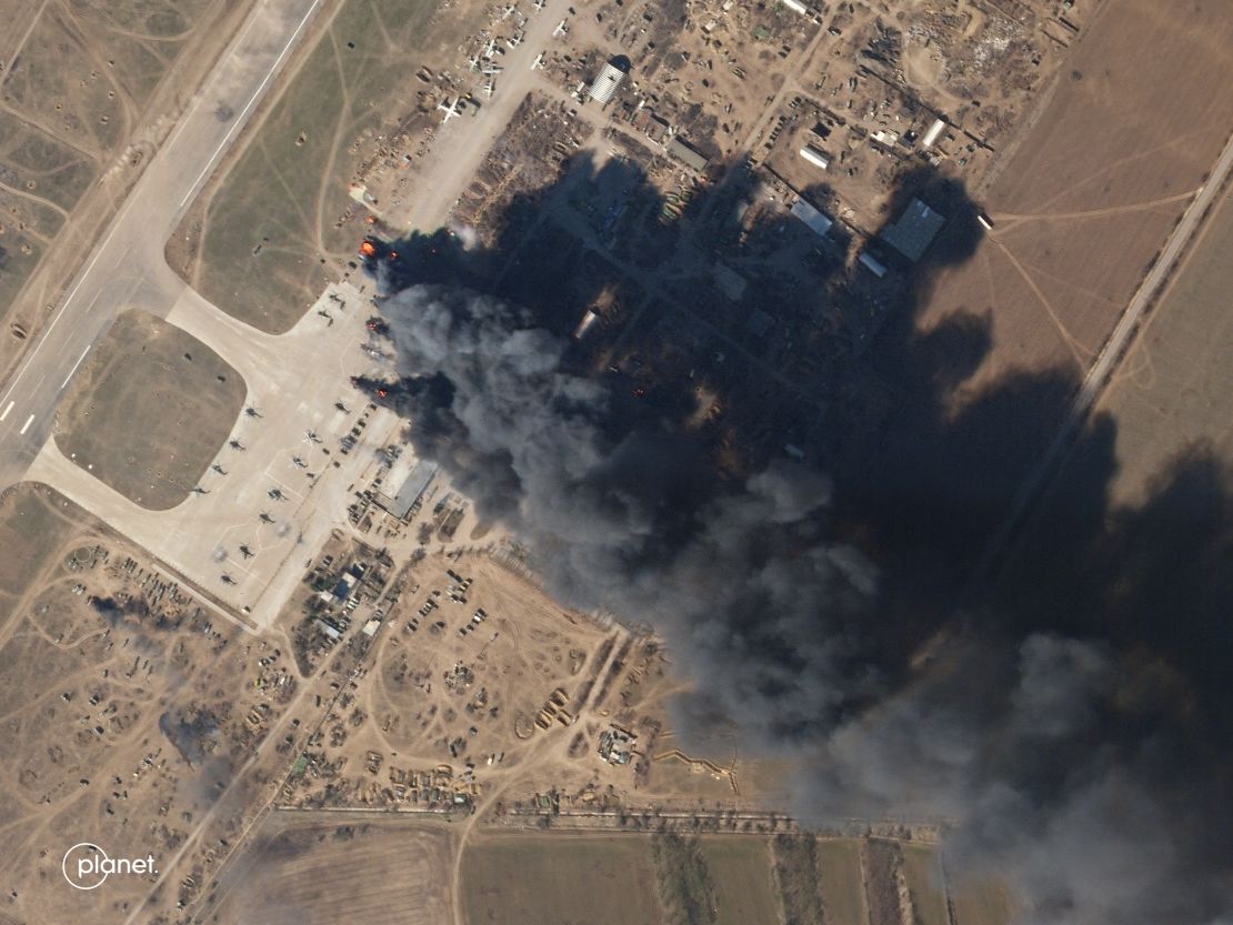 A satellite image shows a large black plume of smoke rising from the Kherson International Airport on Tuesday, March 15. When zoomed in, the satellite images show a number of helicopters are on fire.