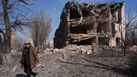 A woman walks past building damaged by shelling in Mariupol on Sunday.