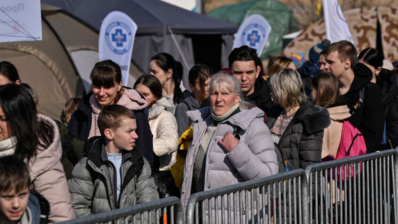 People wait Tuesday to board buses for further transportation after crossing from Ukraine into Poland at the Medyka border crossing.