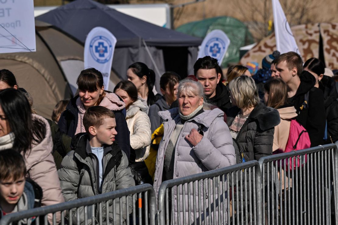 People wait Tuesday to board buses for further transportation after crossing from Ukraine into Poland at the Medyka border crossing.