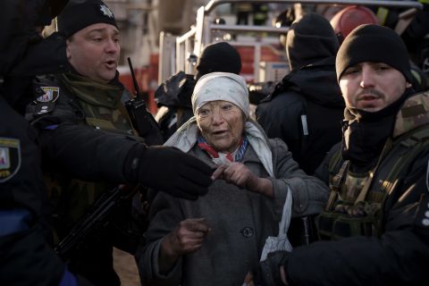 An elderly woman is helped by police officers after she was rescued from an apartment that was hit by shelling in Kyiv on March 15.