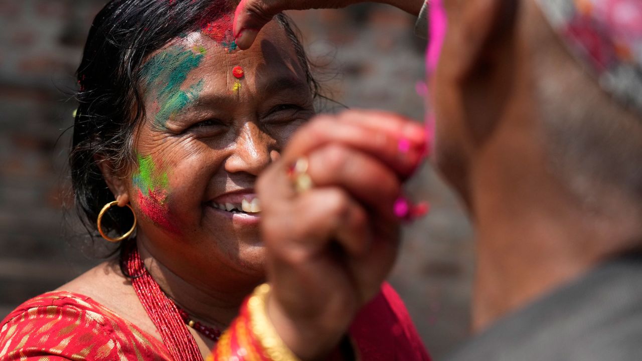 People apply colored powder on each other during Holi celebrations in Bhaktapur, Nepal on March 17, 2022.