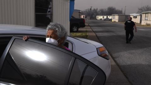 A woman waits for her companions to retrieve belongings from their home Thursday as an Abilene police officer checks on other people evacuating a mobile home park.