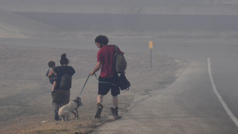 A family walks through smoke Thursday after evacuating a mobile home park in Abilene, Texas. 