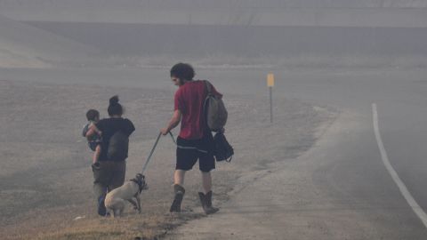 A family walks through smoke Thursday after evacuating a mobile home park in Abilene, Texas.