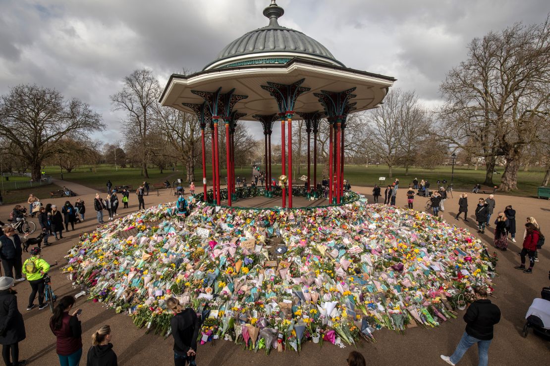 People look at flowers placed in tribute to Sarah Everard on Clapham Common in London on March 15, 2021. 