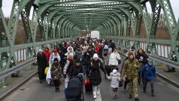 Ukrainian refugees walk a bridge at the buffer zone with the border with Poland in the border crossing of Zosin-Ustyluh, western Ukraine on March 6, 2022. 