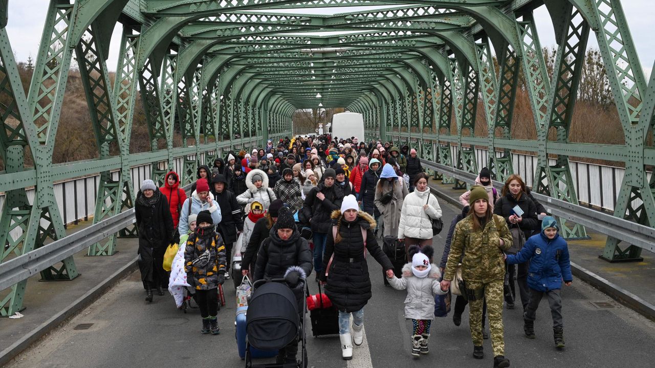 Ukrainian refugees walk a bridge at the buffer zone with the border with Poland in the border crossing of Zosin-Ustyluh, western Ukraine on March 6, 2022.