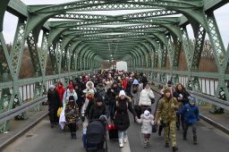 Ukrainian refugees walk a bridge at the buffer zone with the border with Poland in the border crossing of Zosin-Ustyluh, western Ukraine on March 6, 2022. 