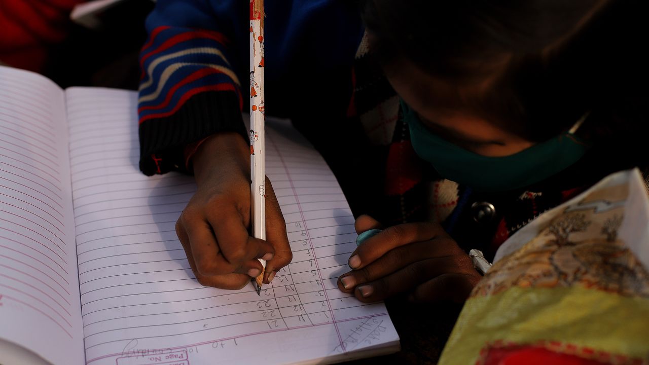 Underprivileged children study at an improvised classroom set up beneath a bridge under construction in New Delhi on January 24. Many children are unable to afford laptops or tablet computers needed for online classes, leaving them without access to education amid the Covid-19 pandemic. The improvised school is provided tuition-free by graduate students.