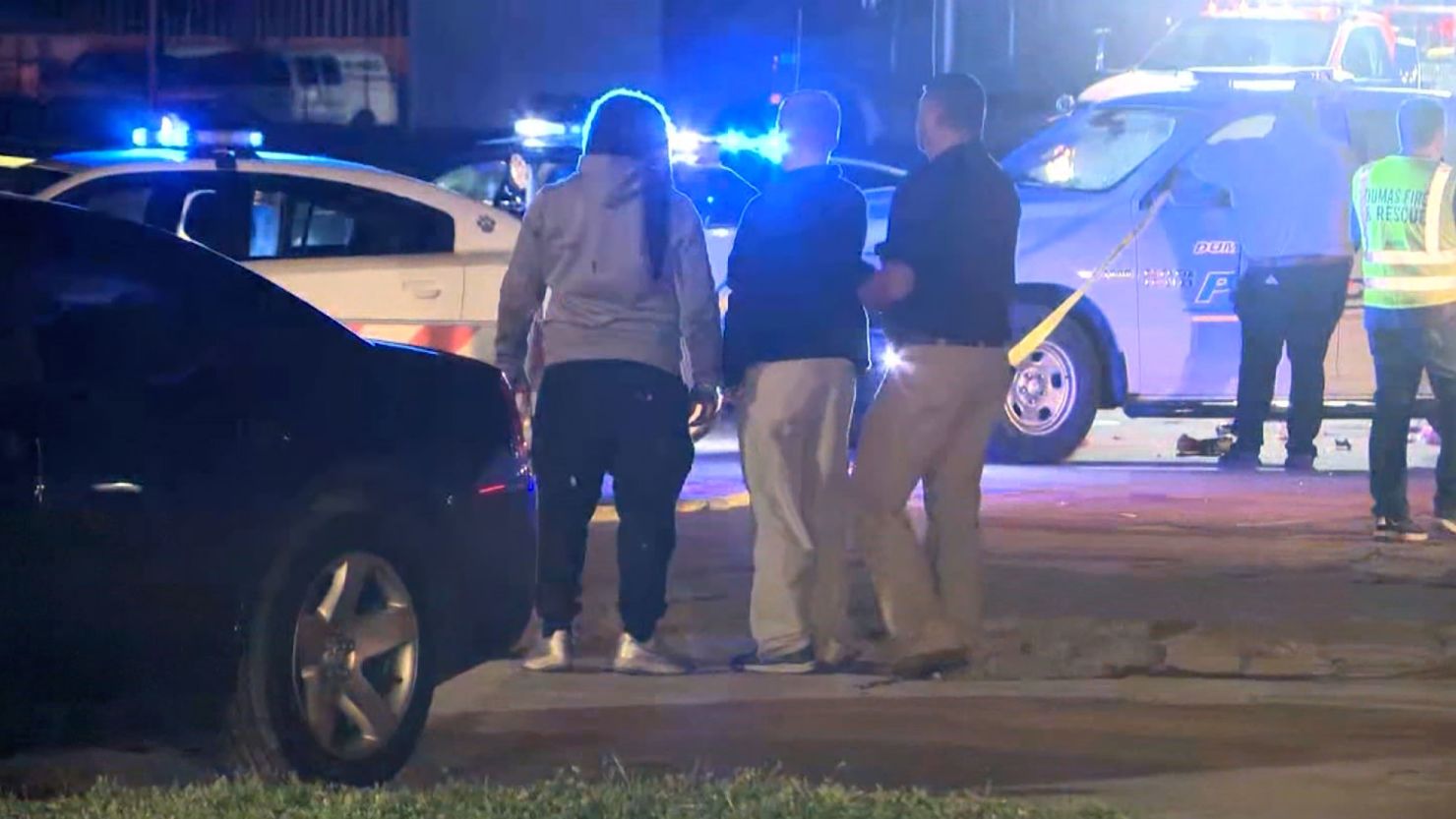 People stand near the scene of a shooting Saturday, March 19, 2022, at a car show in Dumas, Arkansas.