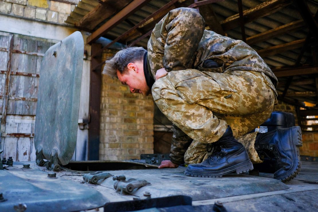 A Ukrainian soldier peeks inside a captured Russian armored personnel carrier that has been painted in Ukrainian colors.