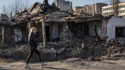ZHYTOMYR, UKRAINE - MARCH 20: A woman walks past a rocket crater and a destroyed home destroyed that was struck in a recent Russian attack on March 20, 2022 in Zhytomyr, Ukraine. Russian forces remain on the outskirts of the Ukrainian capital, but their advance has stalled in recent days, even while Russian strikes - and pieces of intercepted missiles - have hit residential areas in the north of Kyiv. An estimated half of Kyiv's population has fled to other parts of the country, or abroad, since Russia invaded on February 24. (Photo by Chris McGrath/Getty Images)