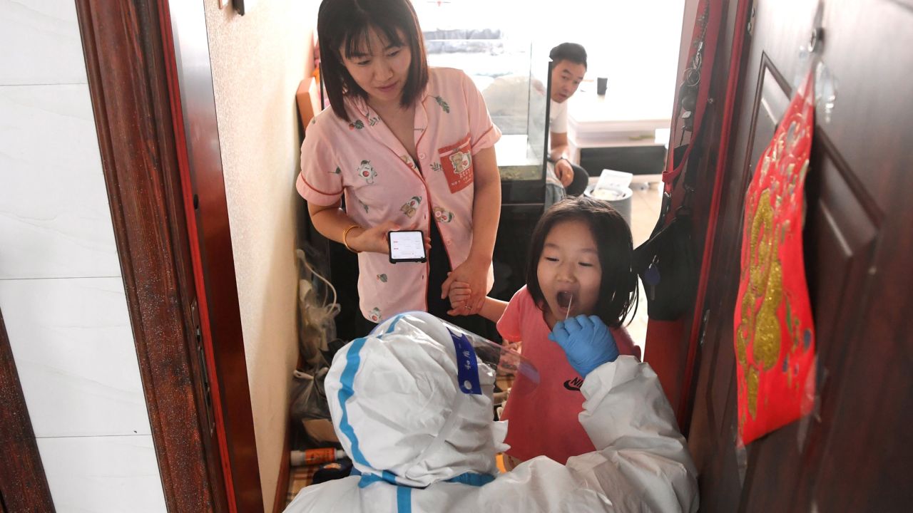 A medical worker takes a swab sample from a resident for nucleic acid test at a community of Jiutai District in Changchun, northeast China's Jilin Province on March 18, 2022. 