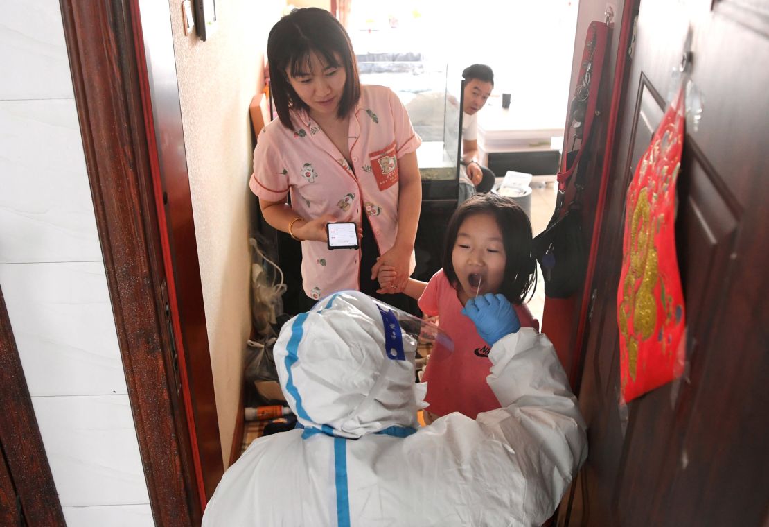 A medical worker takes a swab sample from a resident for nucleic acid test at a community of Jiutai District in Changchun, northeast China's Jilin Province on March 18, 2022. 
