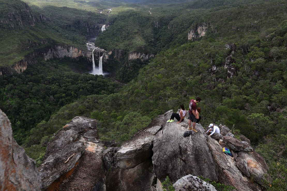 Visitors rest on a rock formation near the Saltos do Rio Preto waterfall in Chapada dos Veadeiros. 