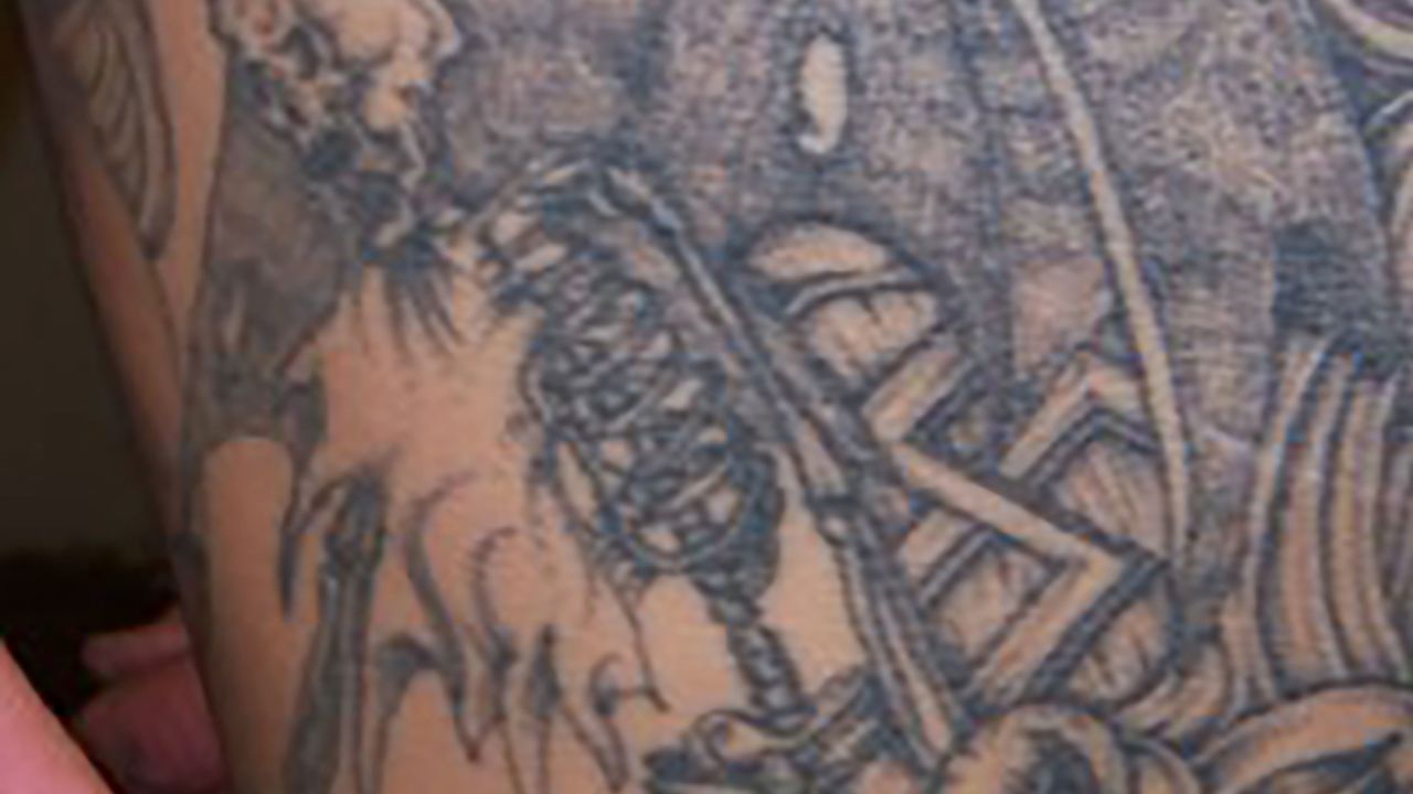 A photo of Jeremy Jones' tattoos revealing a swastika below the wing of a skeleton. 