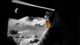 An illustration of a suited Artemis astronaut looking out of a Moon lander hatch across the lunar surface, the Lunar Terrain Vehicle and other surface elements.