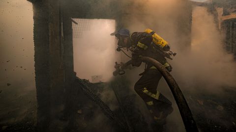A firefighter sprays water inside a house that was destroyed by shelling in Kyiv, Ukraine, on Wednesday, March 23.