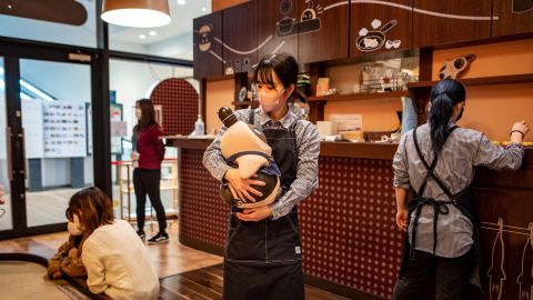 A worker holding a Lovot robot at a cafe in Kawasaki, Japan, is pictured here on Dec. 20, 2020. 