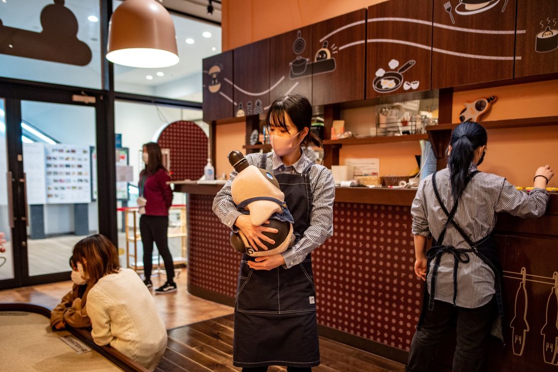 A worker holding a Lovot robot at a cafe in Kawasaki, Japan, is pictured here on Dec. 20, 2020. 