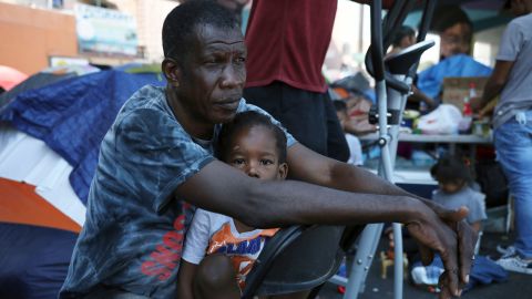 Haitian migrant Dor Louis Hermann holds his 3-year-old son Aadam Jr. at a makeshift camp near the pedestrian border bridge in Tijuana in July.