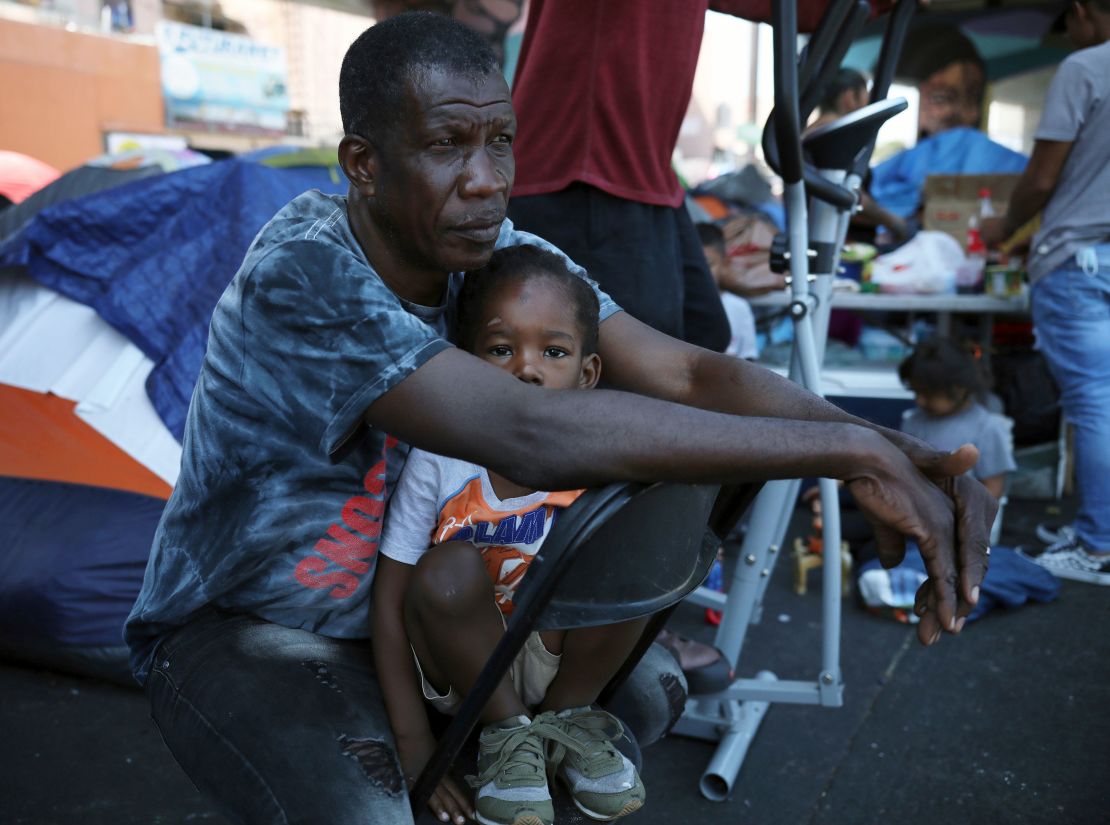 Haitian migrant Dor Louis Hermann holds his 3-year-old son Aadam Jr. at a makeshift camp near the pedestrian border bridge in Tijuana in July.