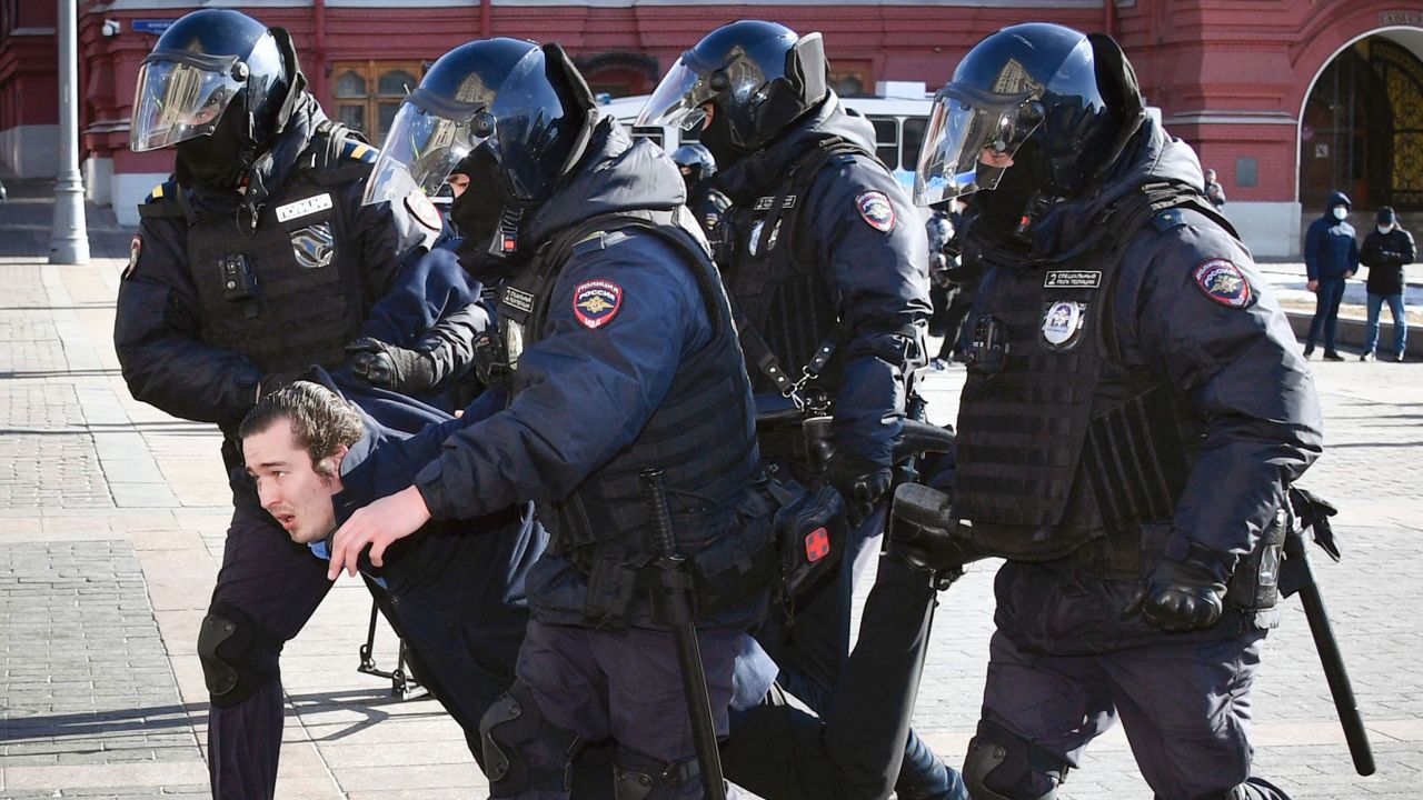 Police officers detain a protester in central Moscow on March 13 -- but no opposition to the war is shown on Russian state-run TV.