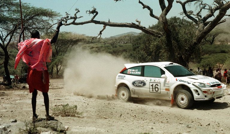 A Maasai warrior watches Petter<strong> </strong>Solberg and Phil Mills compete in the first leg of the 2000 <a href="index.php?page=&url=https%3A%2F%2Fwww.ewrc-results.com%2Fentryinfo%2F110-sameer-safari-rally-kenya-2000%2F7159%2F" target="_blank" target="_blank">Sameer Safari Rally</a>, south of Nairobi. The Norwegian and Briton would finish fifth in the three-day World Rally Championship event.