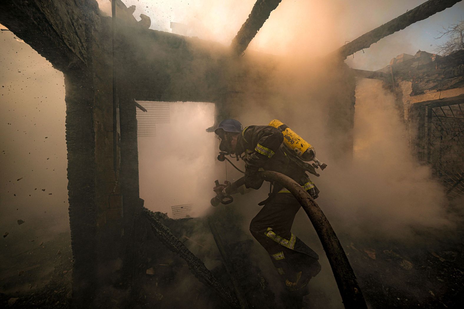 A firefighter sprays water inside a house that was destroyed by Russian shelling in Kyiv, Ukraine, on Wednesday, March 23.
