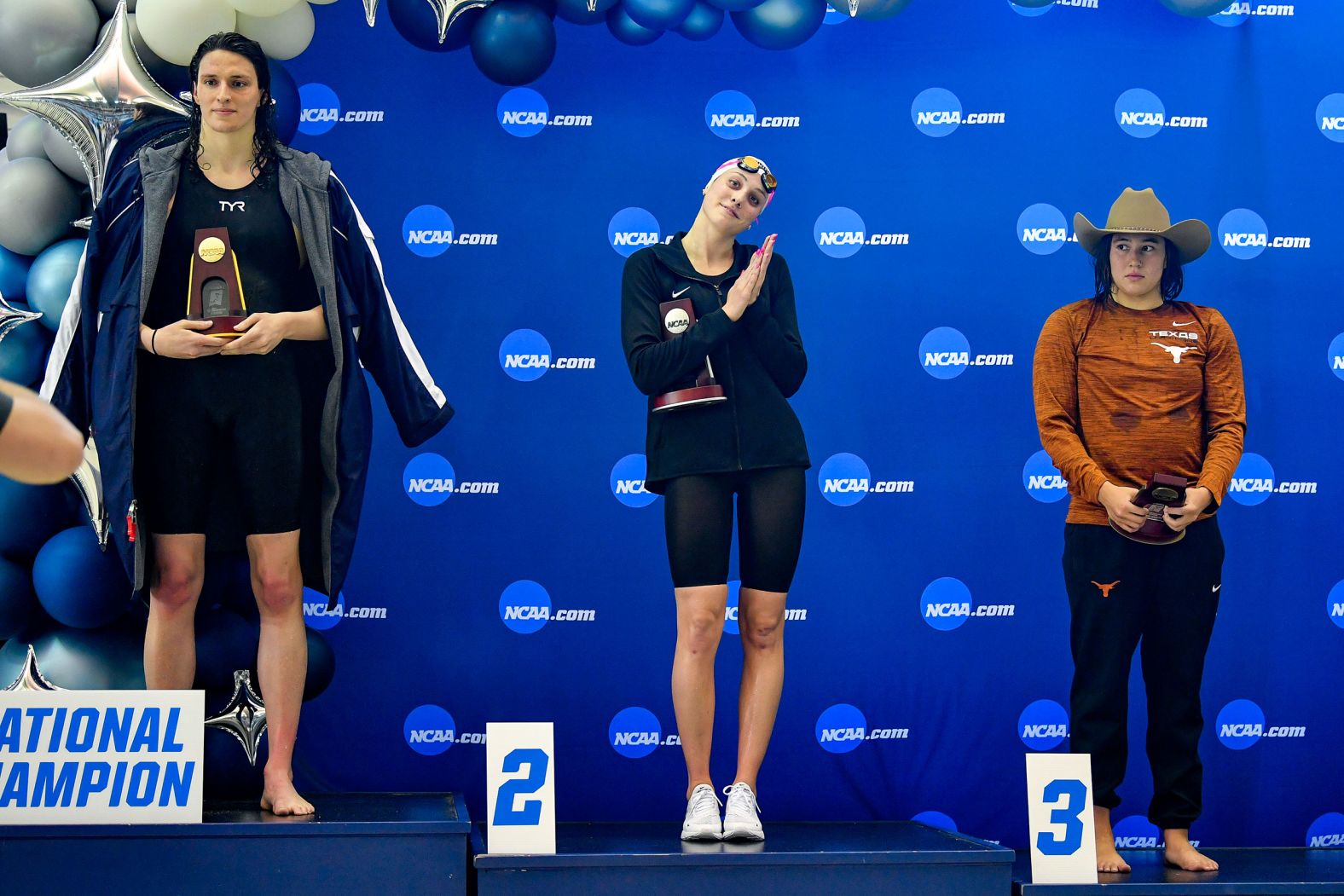 University of Pennsylvania swimmer Lia Thomas, left, accepts her trophy after winning the 500-yard freestyle at the NCAA Championships in Atlanta on Thursday, March 17. Thomas,<a href="index.php?page=&url=https%3A%2F%2Fwww.cnn.com%2F2022%2F03%2F17%2Fsport%2Flia-thomas-ncaa-swimming%2Findex.html" target="_blank"> the first transgender athlete to win an NCAA Division I title,</a> is joined on the podium by second-place Emma Weyant of Virginia and third-place Erica Sullivan of Texas. With each victory, Thomas has brought renewed attention to <a href="index.php?page=&url=https%3A%2F%2Fwww.cnn.com%2F2022%2F02%2F22%2Fus%2Flia-thomas-transgender-swimmer-ivy-league%2Findex.html" target="_blank">the ongoing debate on trans women's participation in sports</a> and the balance between inclusion and fair play.