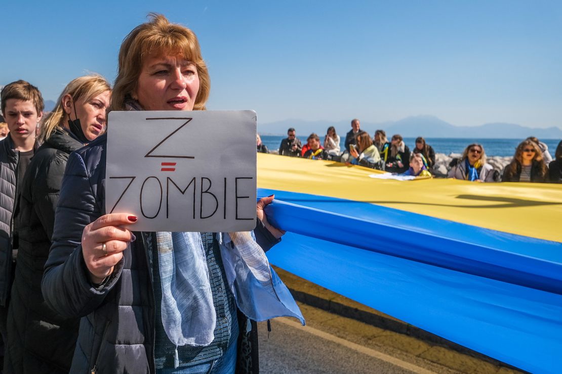 A woman holds a placard that reads "Z = Zombie" at a march in Naples, Italy.