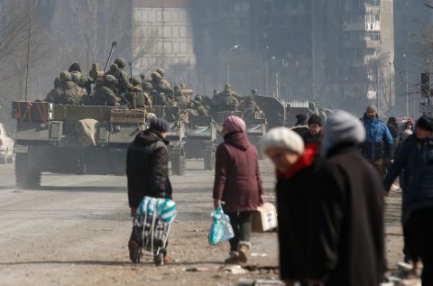 Pro-Russian troops drive armored vehicles past local residents into the besieged southern port city of Mariupol, Ukraine, on Thursday, March 24.