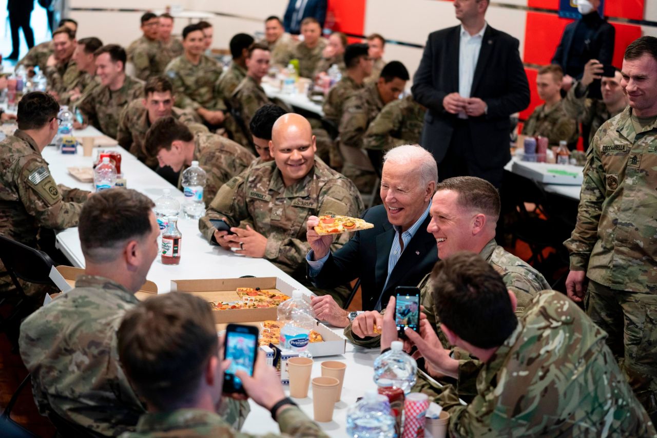 Biden eats a slice of pizza while meeting with members of the 82nd Airborne Division.
