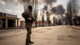 TOPSHOT - A Ukrainian serviceman stands guard near a burning warehouse hit by a Russian shell in the suburbs of the capital Kyiv on March 24, 2022. - The UN General Assembly on March 24, 2022, adopted a new non-binding resolution that demanded an "immediate" halt to Russia's war in Ukraine. At UN headquarters in New York, 140 countries voted in favor, 38 abstained and five voted against the measure, with applause ringing out afterwards. 