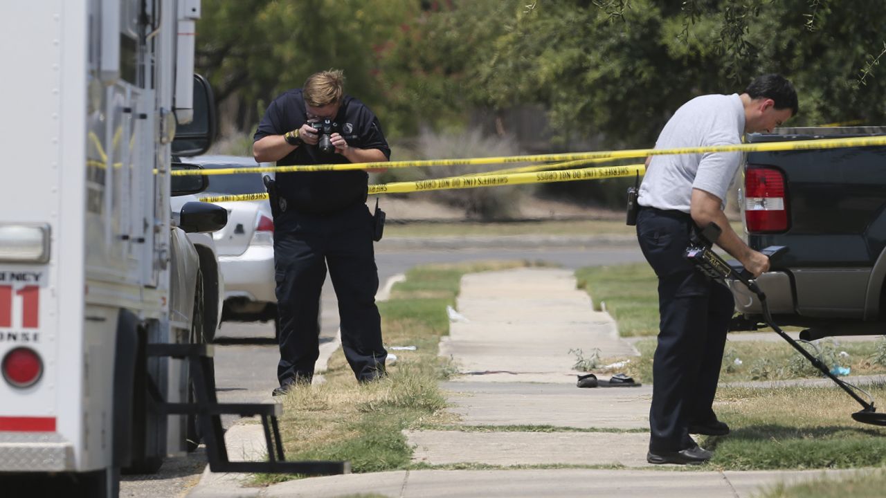 In this August 28, 2015, photo, members of the Bexar County Sheriff's Department investigate the scene where Gilbert Flores was fatally shot.
