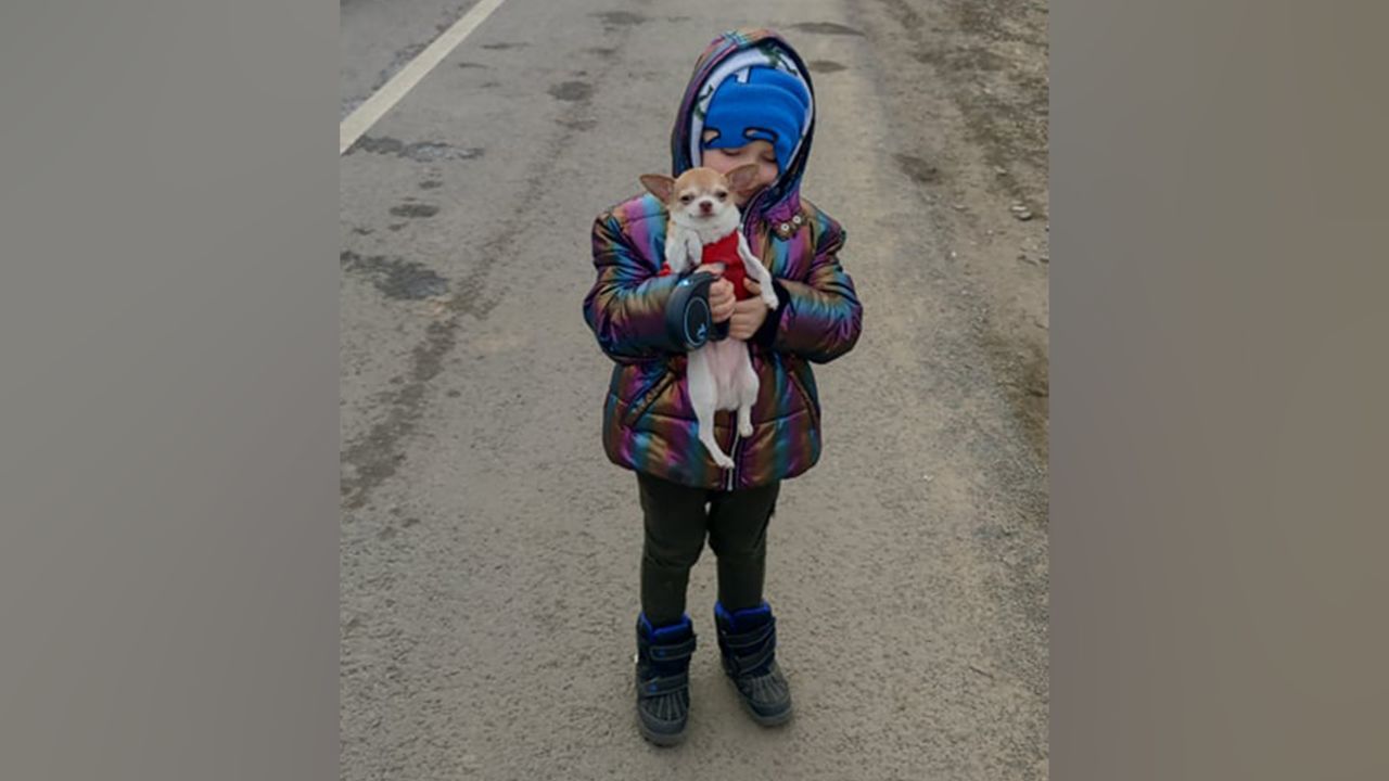 Five year old Milan keeps his spirits up with a friend's dog during stalemate traffic at a Poland checkpoint.