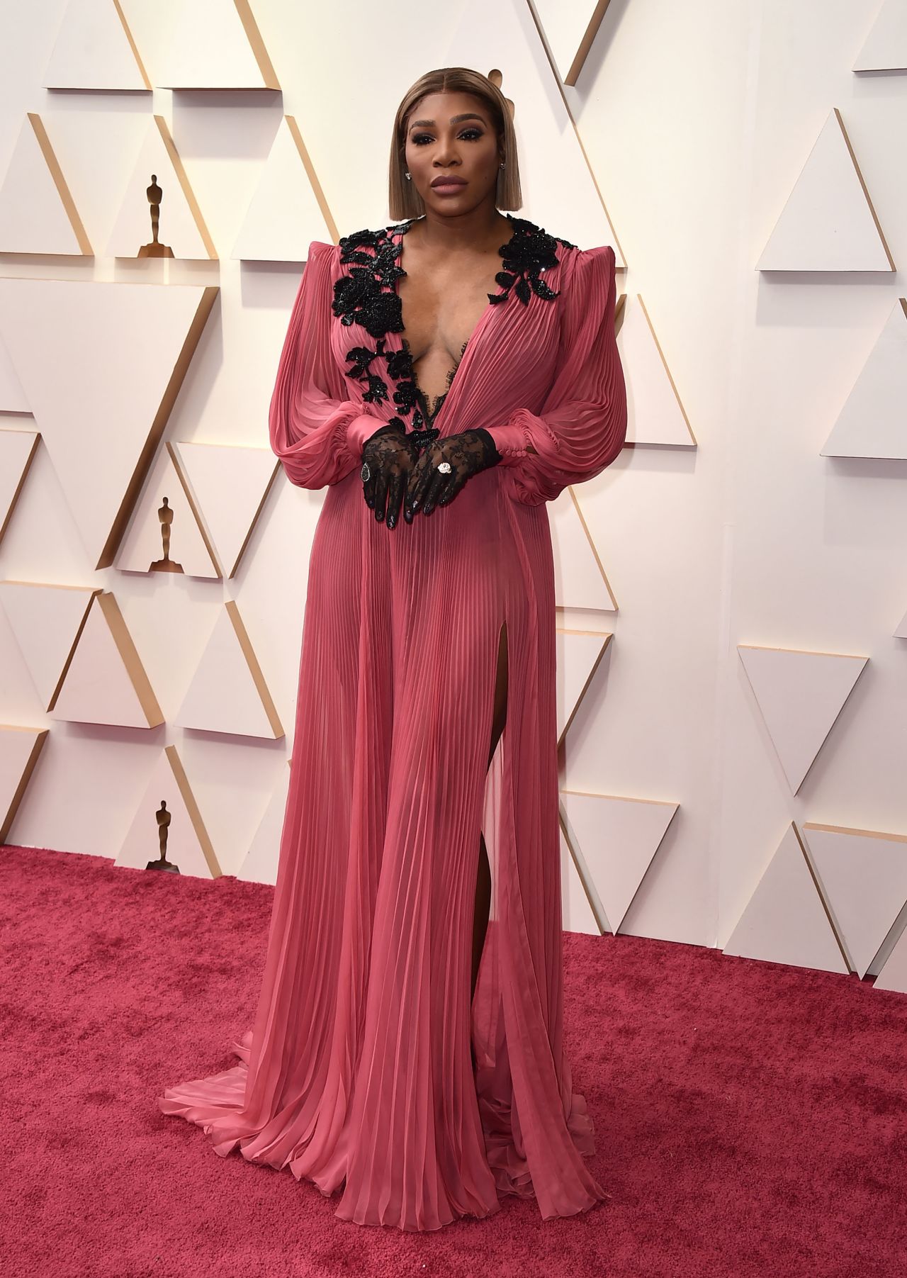 Oscars presenter Serena Williams, co-executive producer of "King Richard" alongside Venus Williams, paired black lace gloves with a flowing Gucci look.  